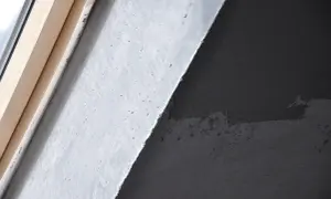 Fragment ściany z betonem architektonicznym i drewnianą ramą okienną. Zastanawiasz się, jak usunąć beton architektoniczny ze ściany?