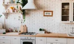 Inspiracja do tego, jak zrobić blat kuchenny z płytek ceramicznych. Jasna kuchnia z drewnianym blatem, białą cegłą i roślinami.