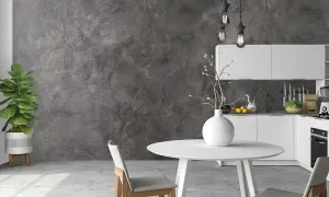 Nowoczesna kuchnia z betonową ścianą, która pokazuje, jak położyć beton na ścianie. Białe meble, okrągły stół i krzesła.
