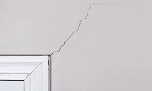 Pęknięcie na ścianie przy drzwiach, które można naprawić akrylem na pęknięcia.
