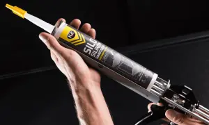 Dłoń trzyma pistolet z tubą silikonu sanitarnego K2. Czy można kłaść silikon na nowy silikon? Ten produkt pomoże Ci to sprawdzić.