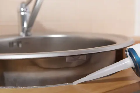 Aplikacja silikonu uniwersalnego bezbarwnego wokół zlewu kuchennego.