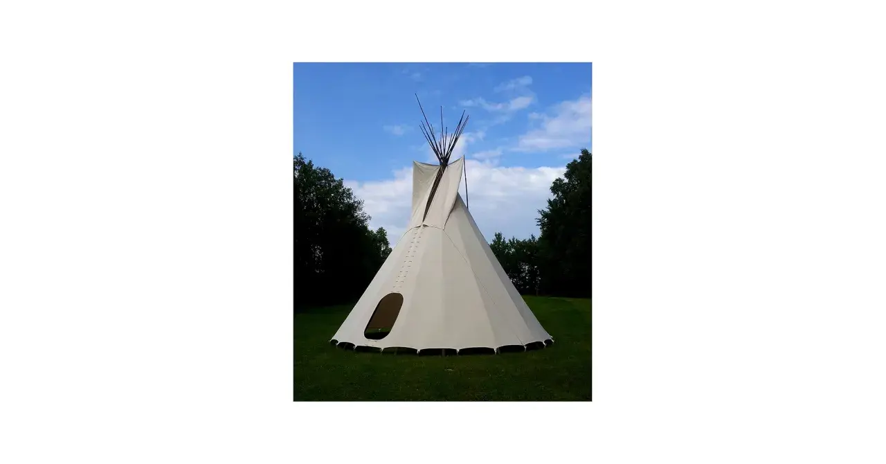 Gotowe tipi ze stabilizatorem, gotowe do rozłożenia na trawie, pod błękitnym niebem.