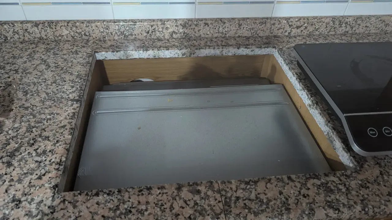 Wycinanie blatu pod płytę indukcyjną. Widać wycięty otwór w granitowym blacie, z zamontowaną płytą.
