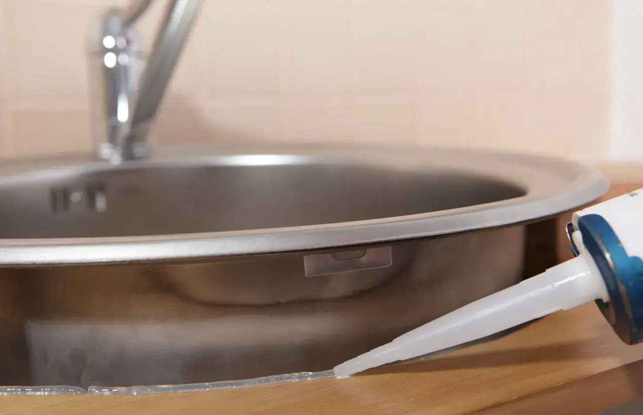Aplikacja silikonu uniwersalnego bezbarwnego wokół zlewu kuchennego.