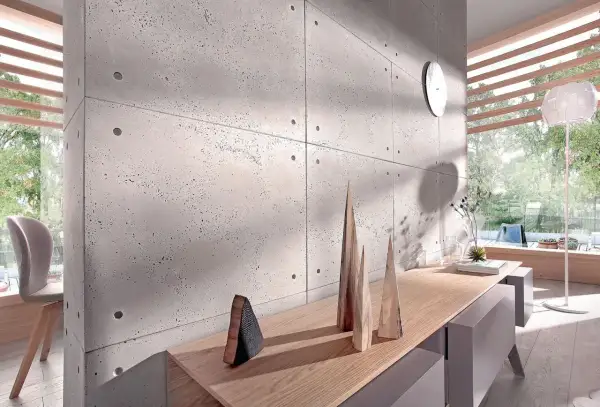 Nowoczesna ściana z betonu architektonicznego, inspiracja jak kłaść beton dekoracyjny na ścianę. Drewniane dekoracje i światło tworzą przytulną atmosferę.