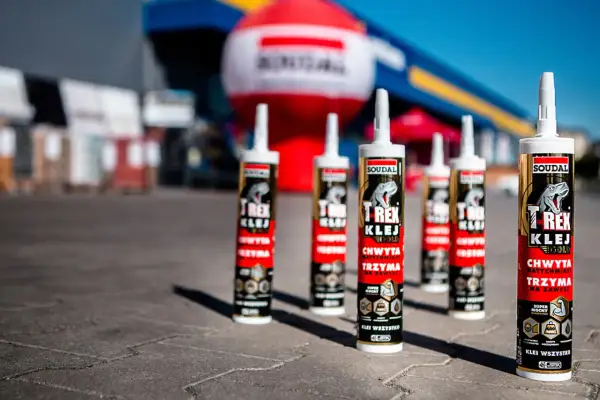 Soudal T-Rex Gold - klej, który chwyta natychmiast i trzyma na zawsze. Kilka tub na tle niebieskiego nieba i balonów.