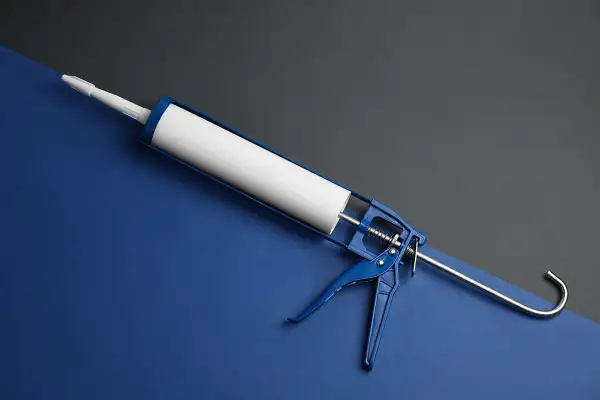 Niebieski pistolet do silikonu z białą tubą. Czy benzyna ekstrakcyjna rozpuszcza silikon? To pytanie nurtuje wielu majsterkowiczów.